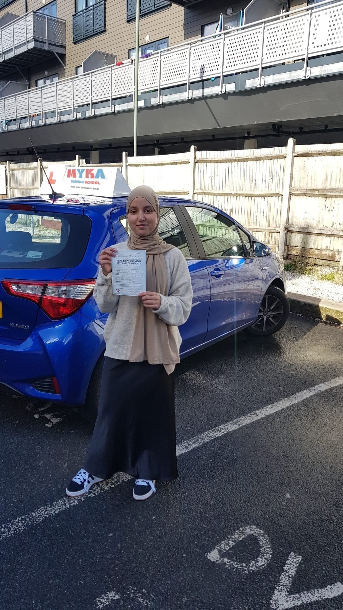a woman holding a paper in front of a blue car