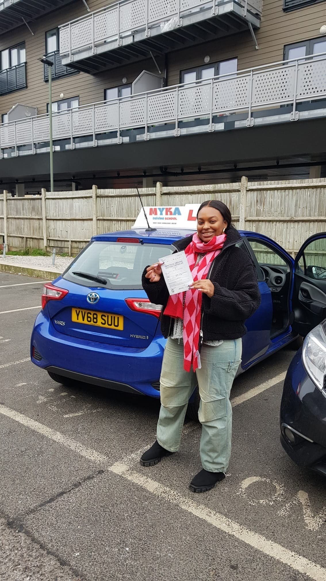 a woman holding a paper in front of a blue car